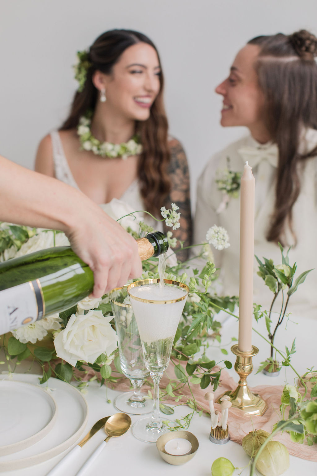 champagne being poured next to white and green florals on a Seattle microwedding table indoors