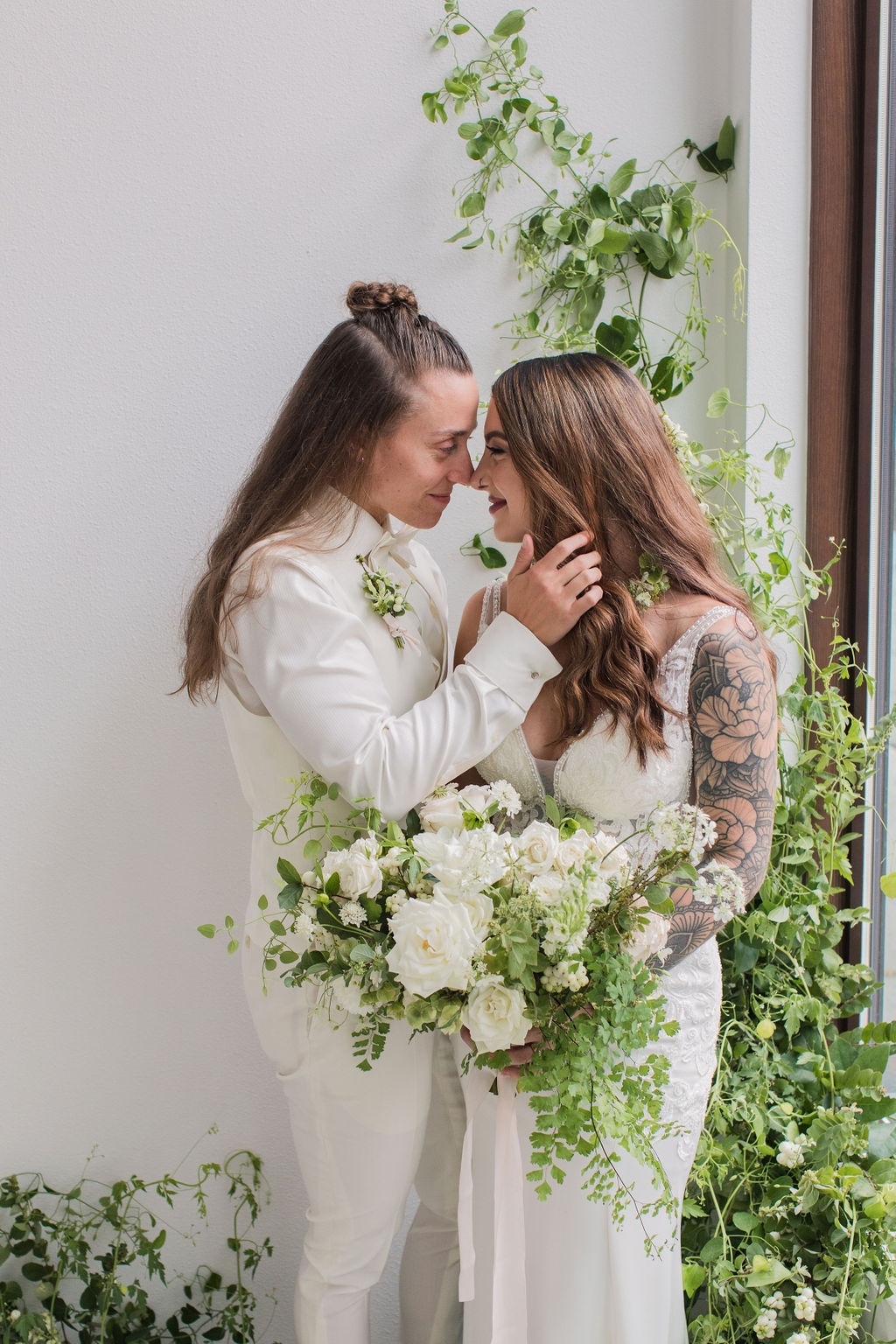 Two lesbian brides at an indoor wedding with green and white decor