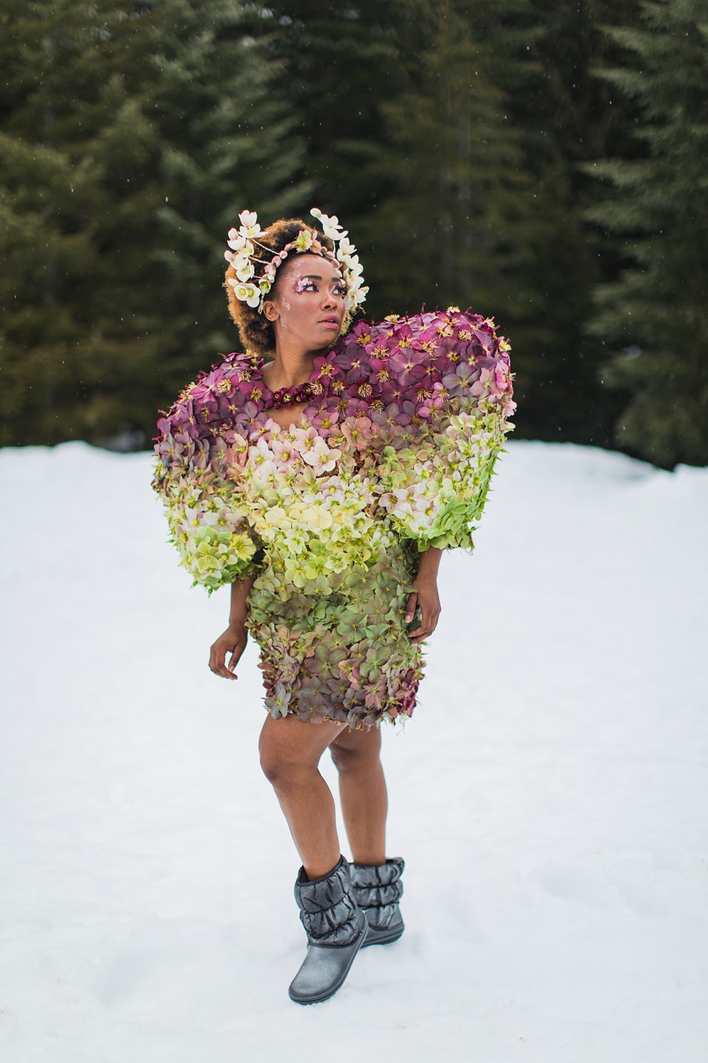 A woman in a dress made of hellebores with a crown made of hellebores in the snow