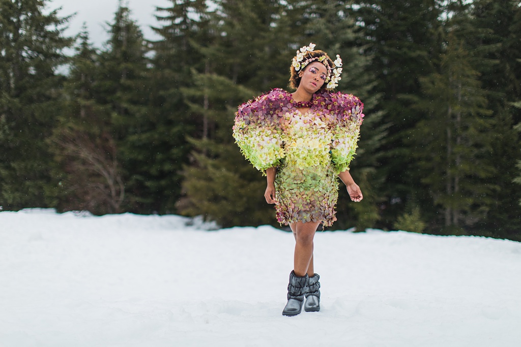 A landscape shot of the hellebore couture dress against the pine trees and snow