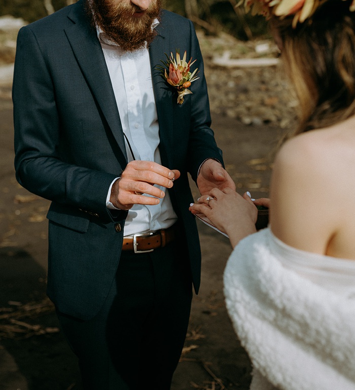 the groom puts a ring on his bride in a beautiful beachfront elopement ceremony in washington on the olympic peninsula