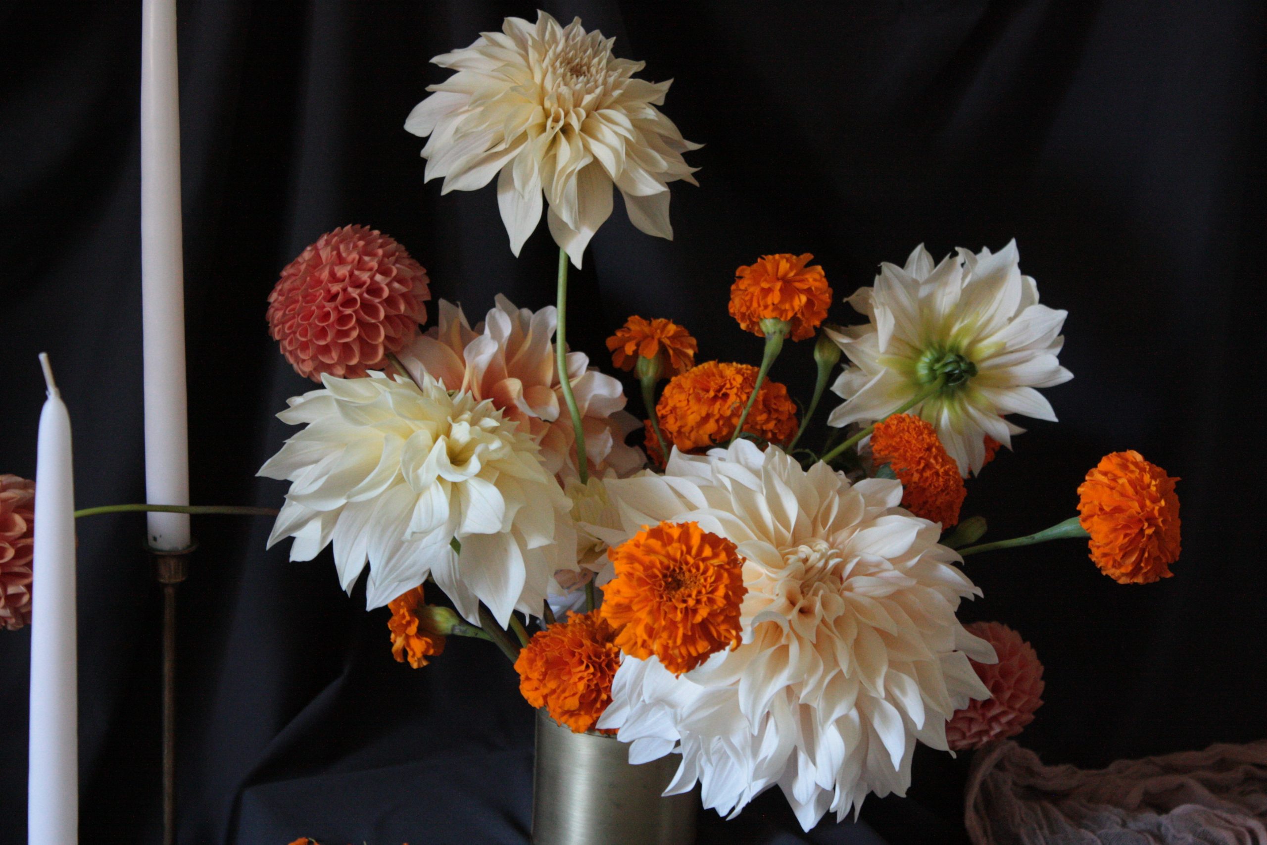 a halloweeny centerpiece with orange marigolds and neutral cafe au lait dahlias