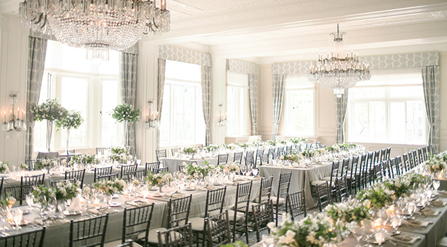 the indoor space of the rainier club, with long tables, crystal chandeliers, high windows, and beautiful molded ceilings